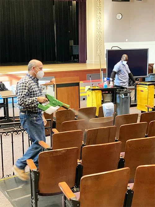Custodians clean and disinfect seats in an auditorium to prevent the spread of COVID-19.