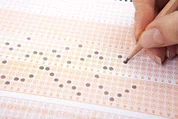 A hand filling out a scantron sheet.