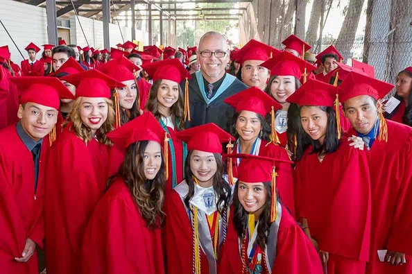 John Briquelet with students in graduation caps an