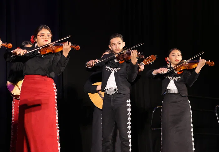 Students perform mariachi music for attendees.