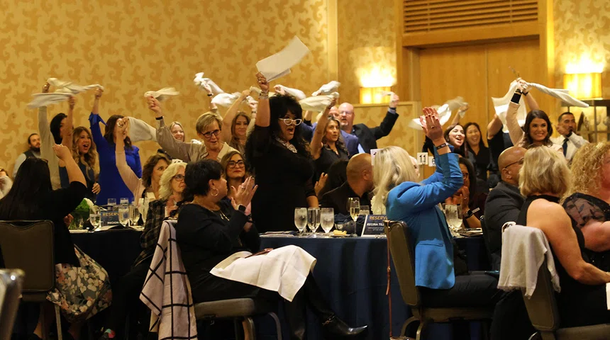 Awards dinner attendees cheer for an award recipient.