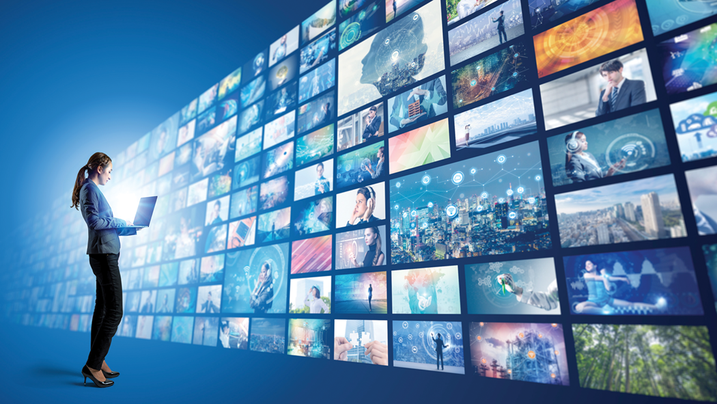 Woman looking at wall of TV screens.