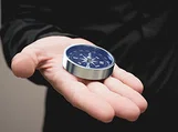 A compass sitting on an open palm.