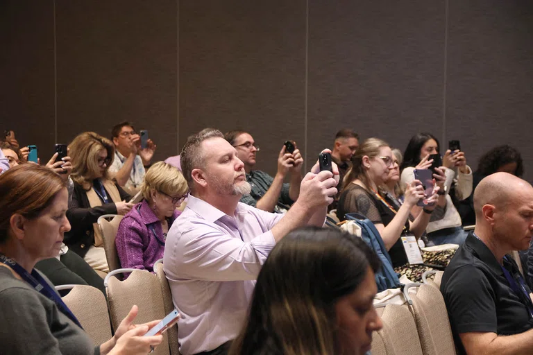 Attendees get out their phones to take a survey.