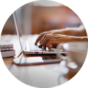 Hands typing on a keyboard with phone and coffee c