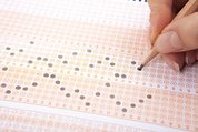 A hand filling out a scantron sheet.