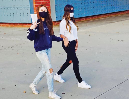 Two high school girls in a peer counselor training, one leading the blindfolded other.