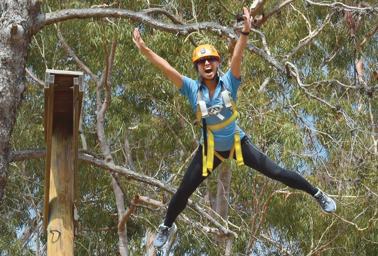 A participant makes the leap on the ropes course at the 2019 institute.